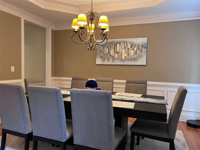 dining room featuring ornamental molding, a tray ceiling, a notable chandelier, and hardwood / wood-style floors