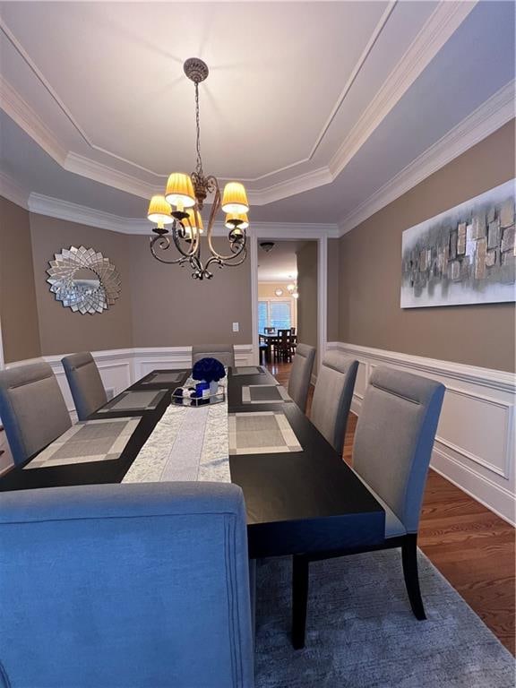 dining area featuring a raised ceiling, a chandelier, dark hardwood / wood-style floors, and ornamental molding