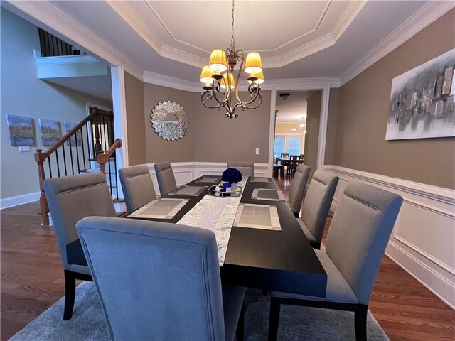 dining room featuring ornamental molding, a tray ceiling, dark hardwood / wood-style floors, and an inviting chandelier