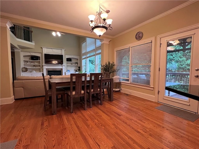 dining space with ornamental molding, a notable chandelier, and wood-type flooring