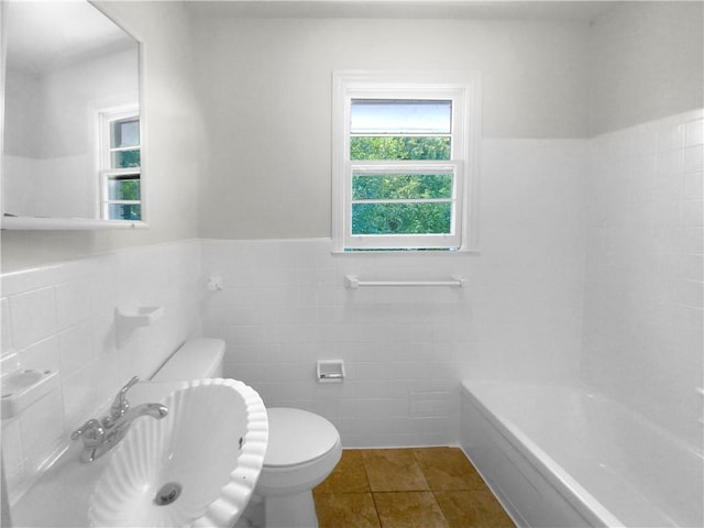 bathroom with tile walls, tile patterned floors, toilet, and a tub