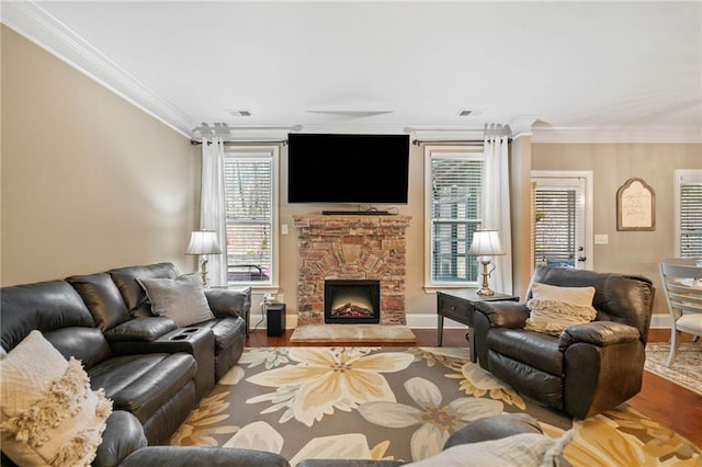 living room with ornamental molding, hardwood / wood-style flooring, and a stone fireplace