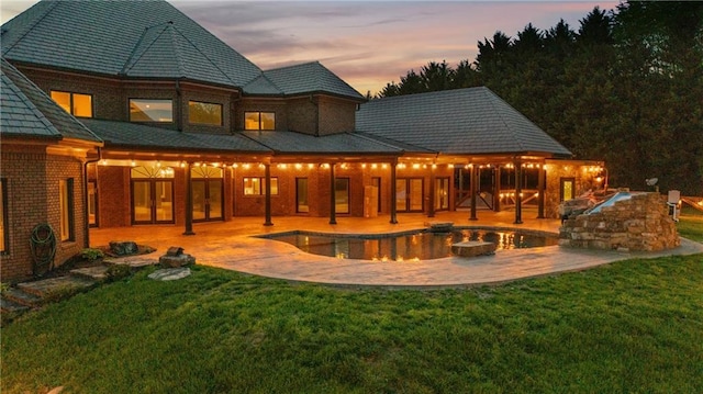 1580 Loving Rd, Morganton, GA 30560 - back of property at dusk with a lawn, a patio area, an outdoor pool, and brick siding