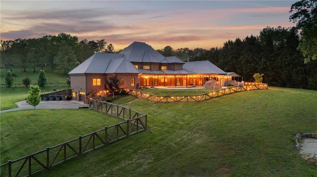1580 Loving Rd, Morganton, GA 30560 - back of house at dusk featuring concrete driveway, an attached garage, a fenced backyard, and a yard