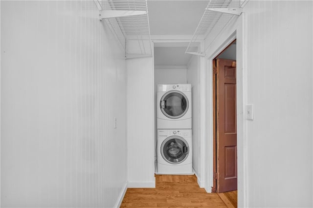 laundry area with stacked washer and clothes dryer and light wood-type flooring