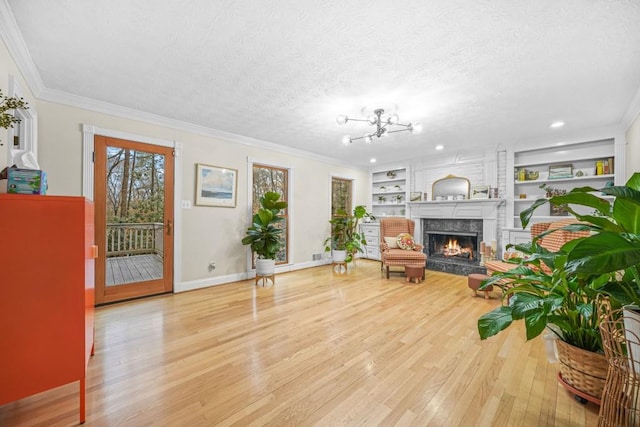 sitting room with built in features, a textured ceiling, wood finished floors, and a high end fireplace