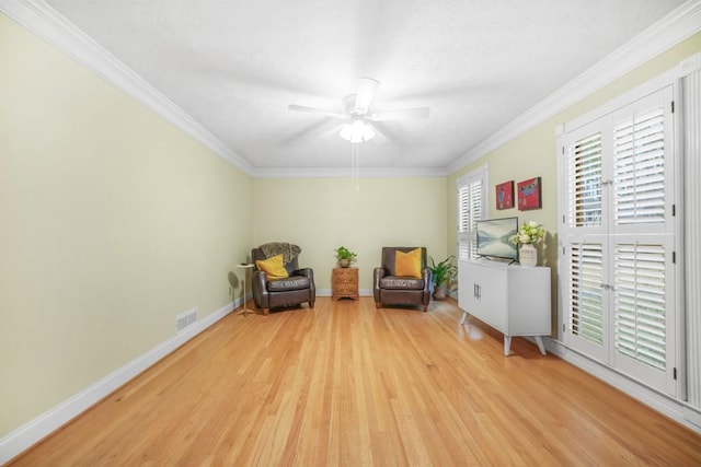 living area with visible vents, crown molding, light wood-type flooring, and baseboards