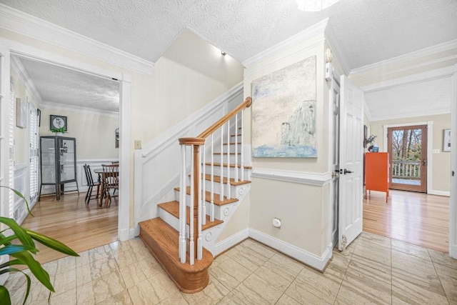 stairway with a textured ceiling, baseboards, and ornamental molding