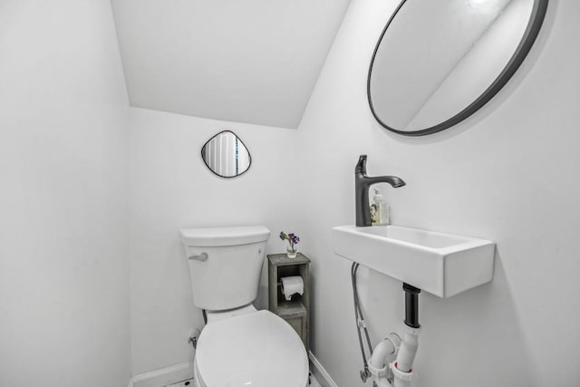 bathroom with a sink, baseboards, toilet, and vaulted ceiling