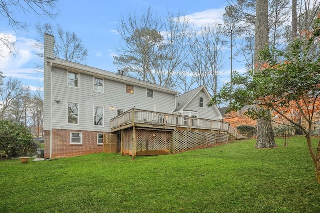 rear view of house featuring a deck, a lawn, brick siding, and a chimney