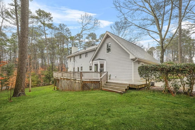 back of house with a wooden deck, a lawn, and a chimney