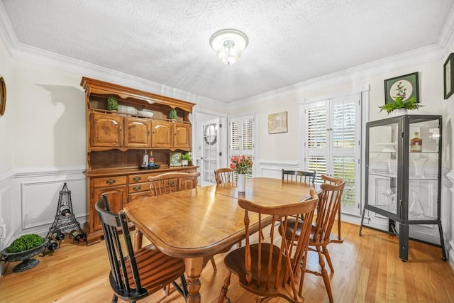 dining room featuring a textured ceiling, light wood-style flooring, and crown molding