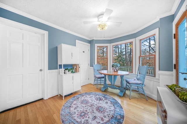 dining room with light wood finished floors, a textured ceiling, crown molding, and a ceiling fan