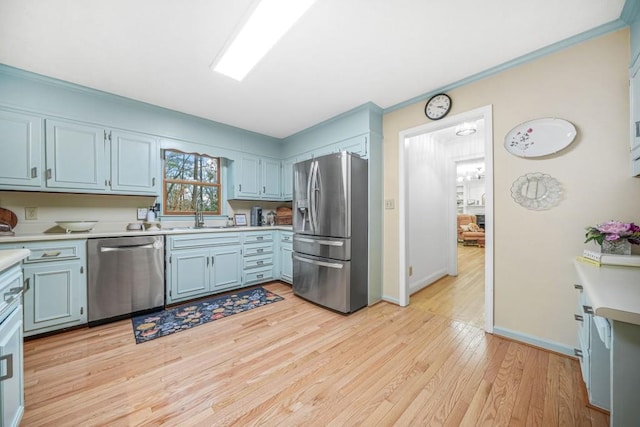 kitchen featuring a sink, light wood-type flooring, appliances with stainless steel finishes, and light countertops