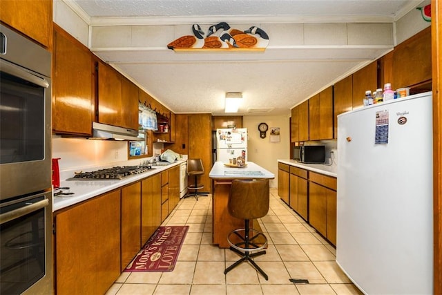 1278 Twin Pine Rd, Milledgeville, GA 31061 - kitchen featuring appliances with stainless steel finishes, light countertops, brown cabinetry, a kitchen island, and crown molding