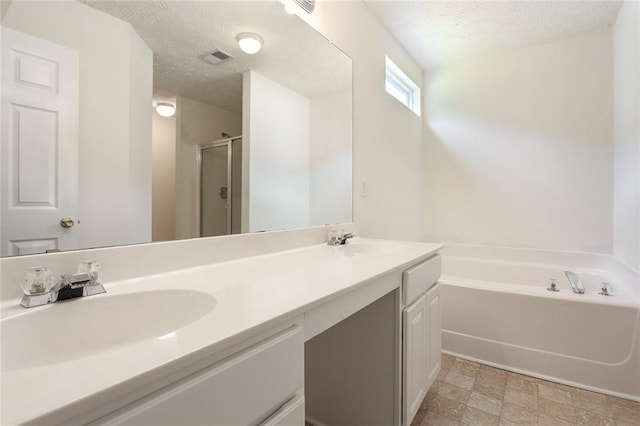 full bath featuring a stall shower, a sink, a textured ceiling, double vanity, and a bath