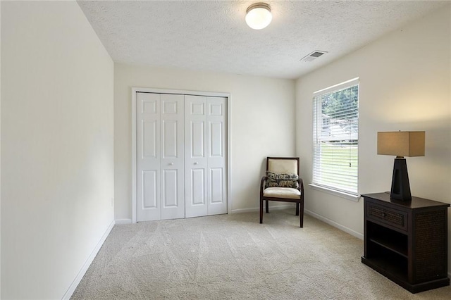 living area with baseboards, visible vents, carpet floors, and a textured ceiling