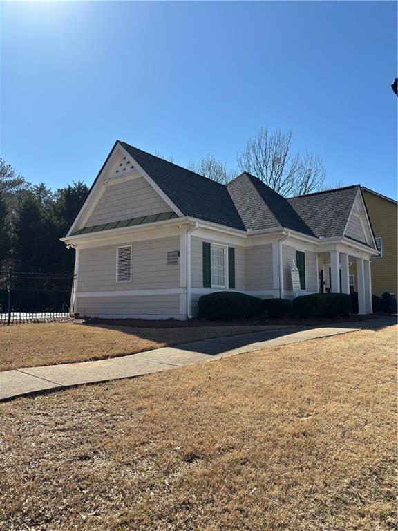 view of front of house with roof with shingles and a front lawn