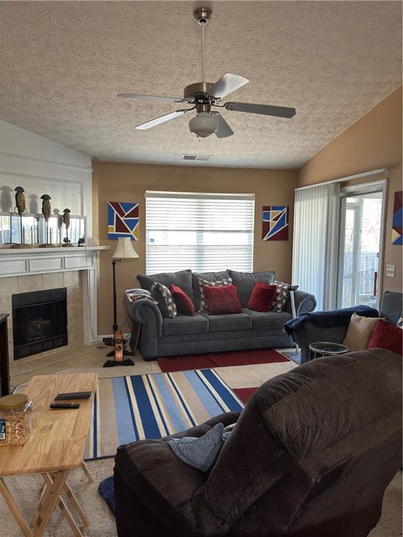 carpeted living area featuring a wealth of natural light, visible vents, lofted ceiling, and a ceiling fan