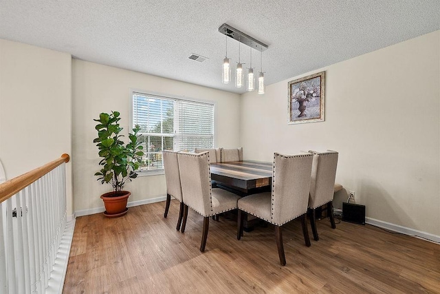 dining space with hardwood / wood-style flooring and a textured ceiling