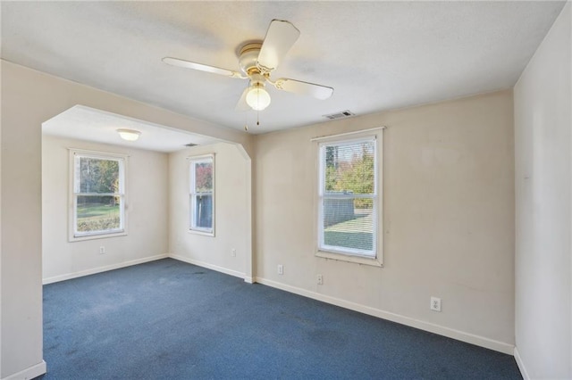 unfurnished room featuring dark colored carpet, visible vents, plenty of natural light, and baseboards