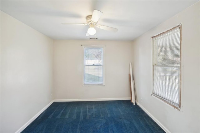 unfurnished room with ceiling fan, dark colored carpet, visible vents, and baseboards