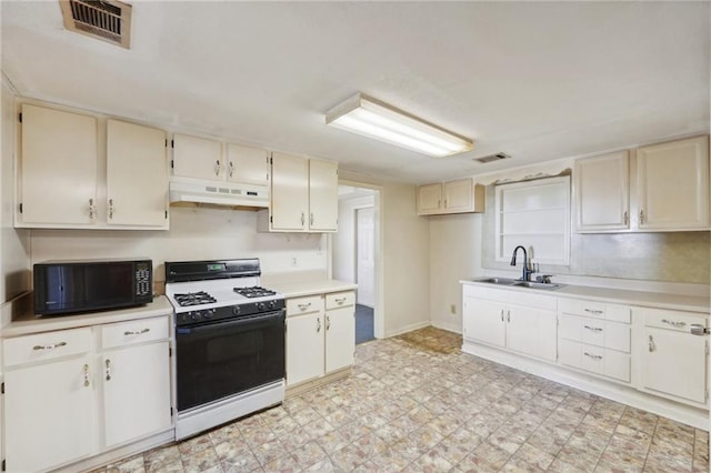 kitchen featuring black microwave, under cabinet range hood, a sink, visible vents, and range with gas cooktop