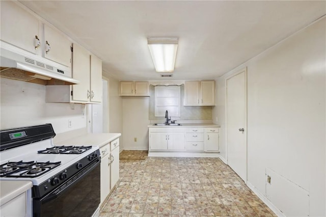 kitchen with under cabinet range hood, a sink, visible vents, light countertops, and gas stove