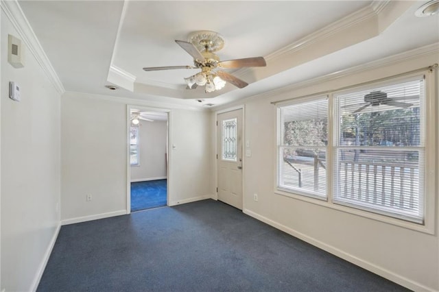 spare room with baseboards, dark colored carpet, a tray ceiling, and crown molding