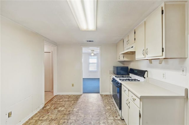 kitchen featuring light countertops, visible vents, gas range, black microwave, and under cabinet range hood