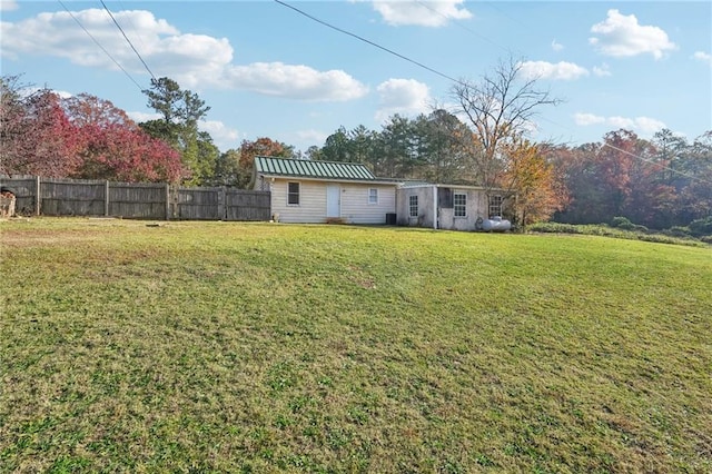 rear view of house with metal roof, fence, a standing seam roof, and a lawn