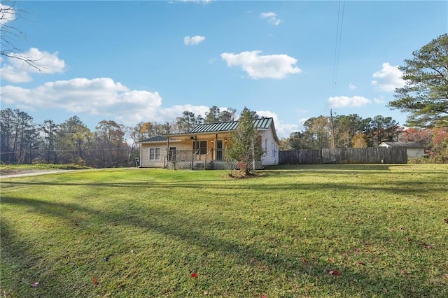 view of front of house with a porch, a standing seam roof, fence, metal roof, and a front lawn