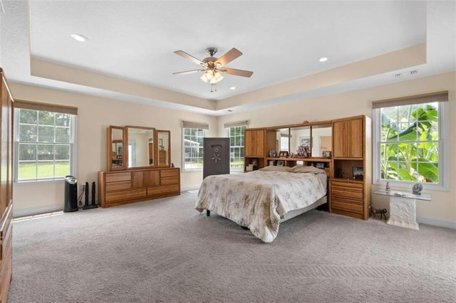 bedroom featuring a raised ceiling, multiple windows, and ceiling fan