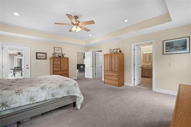 carpeted bedroom featuring connected bathroom, a tray ceiling, and ceiling fan