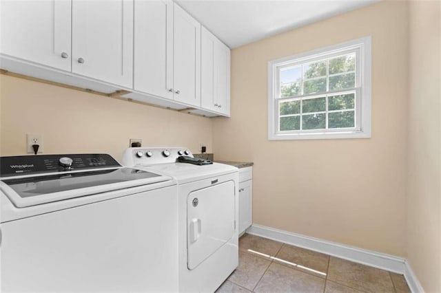 washroom featuring cabinets, washing machine and dryer, and light tile patterned flooring