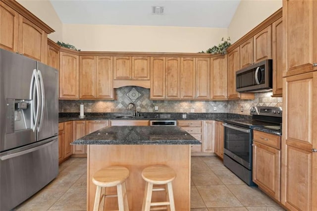 kitchen featuring sink, a kitchen island, light tile patterned flooring, and stainless steel appliances