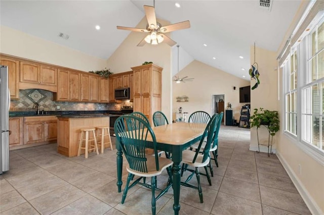 dining room featuring ceiling fan, sink, light tile patterned floors, and high vaulted ceiling