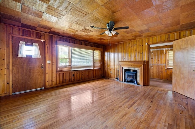 1191 S Burnt Hickory Rd, Douglasville, GA 30134 - unfurnished living room featuring ceiling fan, wood walls, wood finished floors, and a wood stove