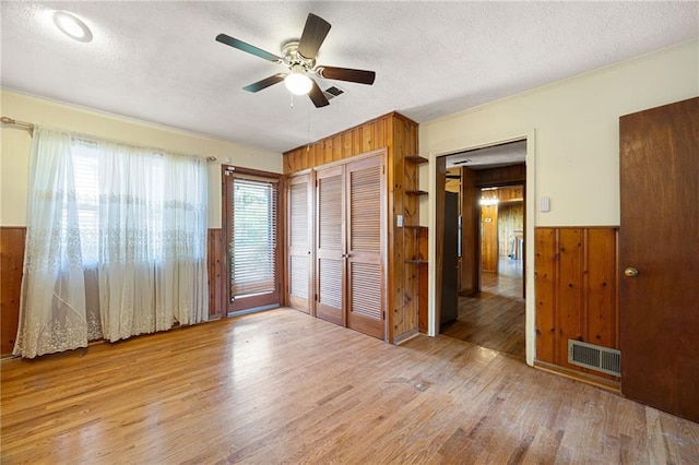 1191 S Burnt Hickory Rd, Douglasville, GA 30134 - unfurnished bedroom featuring wood walls, wood finished floors, a textured ceiling, wainscoting, and ceiling fan