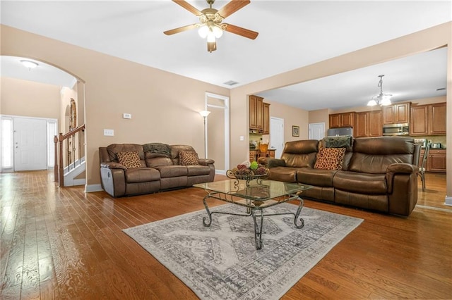 living room featuring arched walkways, baseboards, a ceiling fan, and hardwood / wood-style floors
