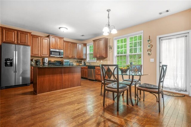 kitchen featuring visible vents, pendant lighting, wood finished floors, an inviting chandelier, and stainless steel appliances