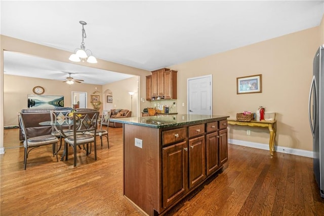 kitchen featuring freestanding refrigerator, a ceiling fan, open floor plan, wood finished floors, and a kitchen island