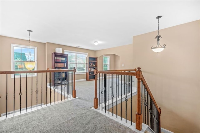 hall featuring baseboards, carpet, and an upstairs landing