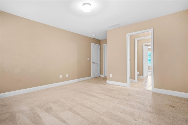 unfurnished bedroom featuring baseboards, visible vents, and light carpet