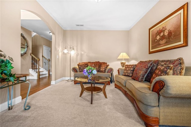 living area with carpet floors, arched walkways, stairway, and ornamental molding