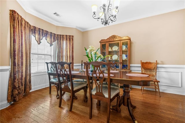 dining space featuring wainscoting, a chandelier, wood finished floors, visible vents, and ornamental molding