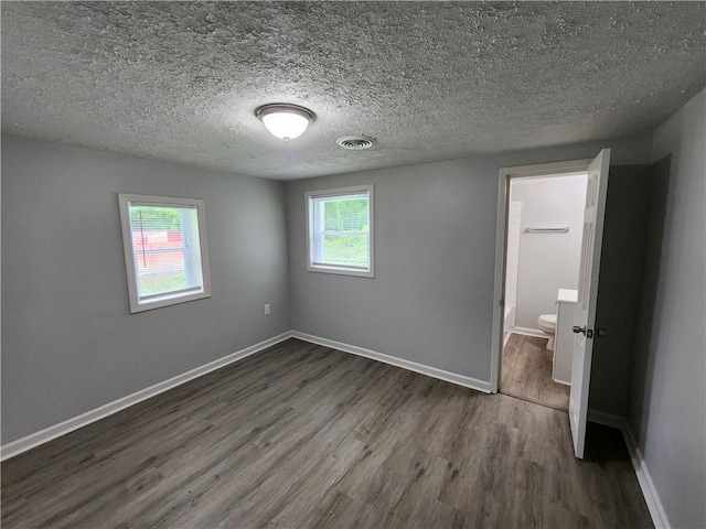 908 Davis St, Monroe, GA 30655 - unfurnished bedroom with dark wood-style floors, baseboards, visible vents, and a textured ceiling