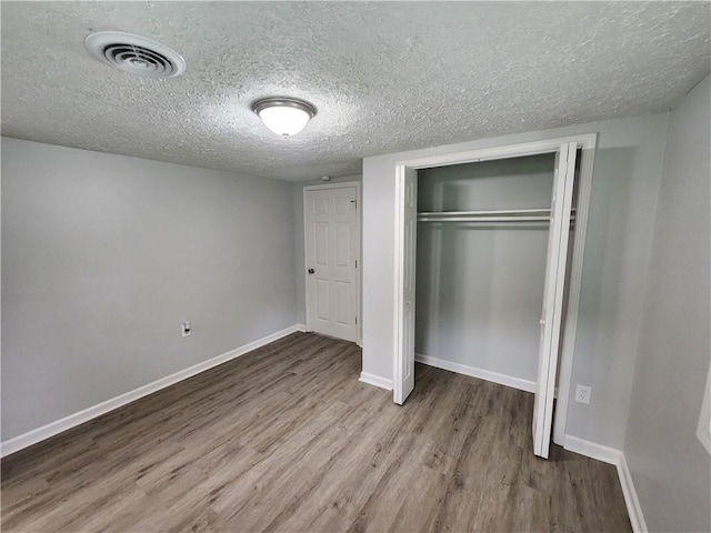 908 Davis St, Monroe, GA 30655 - unfurnished bedroom with a closet, visible vents, a textured ceiling, wood finished floors, and baseboards
