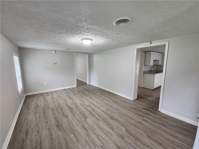 908 Davis St, Monroe, GA 30655 - spare room with baseboards, visible vents, wood finished floors, a textured ceiling, and a sink
