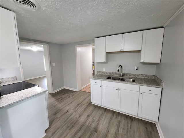 908 Davis St, Monroe, GA 30655 - kitchen with a textured ceiling, a sink, visible vents, white cabinetry, and light wood finished floors